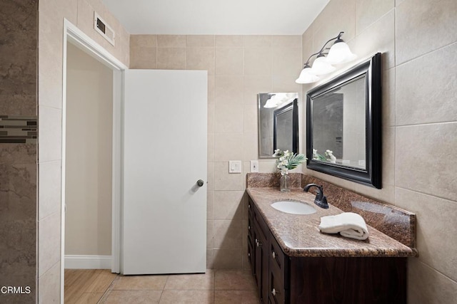 bathroom with tile walls, vanity, and tile patterned floors