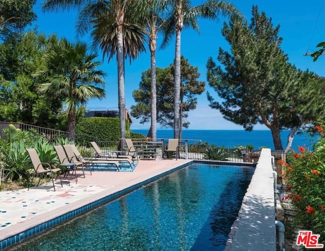 view of swimming pool with a water view and a patio