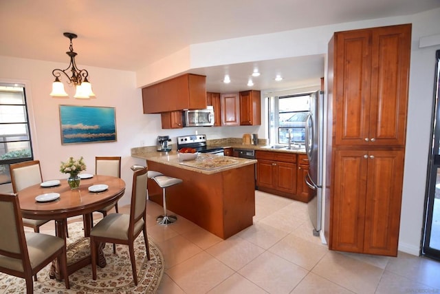 kitchen featuring pendant lighting, light tile patterned floors, a breakfast bar area, stainless steel appliances, and kitchen peninsula