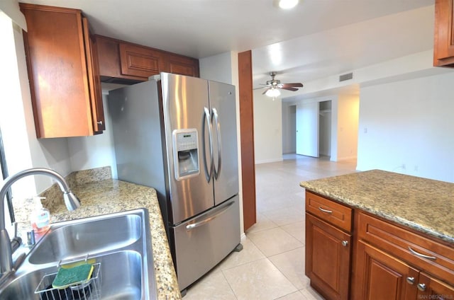 kitchen with sink, stainless steel fridge, light tile patterned floors, ceiling fan, and light stone countertops