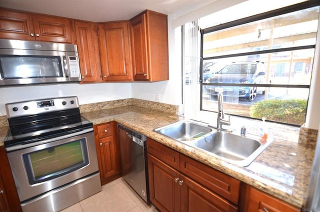 kitchen with stainless steel appliances, light stone countertops, sink, and light tile patterned floors