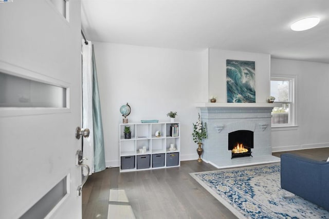 living room featuring a brick fireplace and dark hardwood / wood-style floors