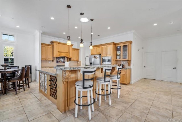 kitchen with crown molding, stainless steel appliances, light stone countertops, a kitchen island with sink, and backsplash