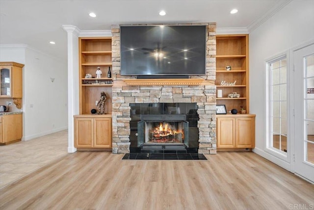 unfurnished living room with built in features, a fireplace, ornamental molding, and light hardwood / wood-style floors