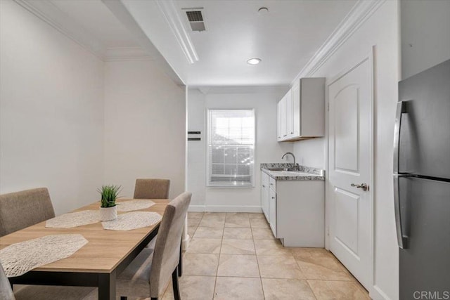 kitchen featuring light tile patterned flooring, sink, white cabinets, stainless steel fridge, and crown molding