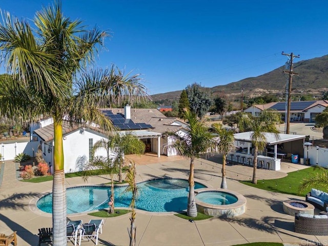 view of pool with a patio area, an outdoor fire pit, an in ground hot tub, a mountain view, and a bar