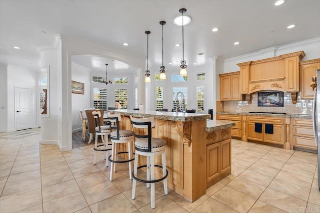 kitchen featuring light tile patterned flooring, a kitchen island, pendant lighting, tasteful backsplash, and light stone countertops