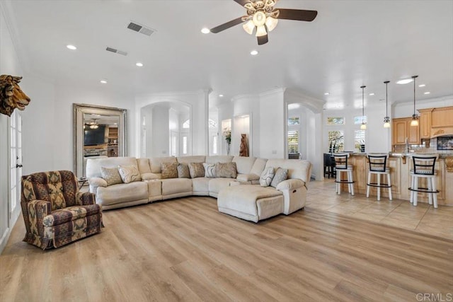 living room featuring crown molding, ceiling fan, and light wood-type flooring