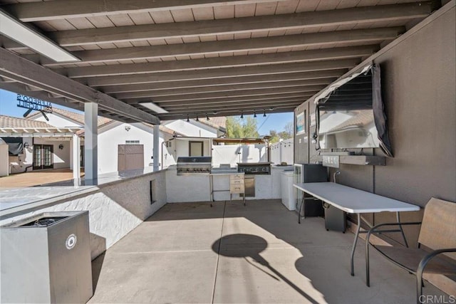 view of patio with exterior kitchen and a grill