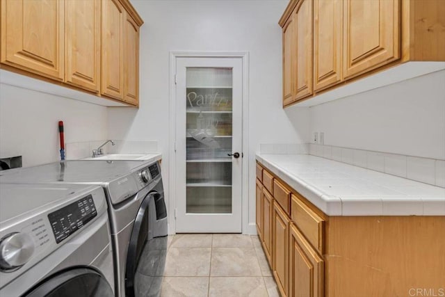 laundry room featuring separate washer and dryer, light tile patterned floors, sink, and cabinets