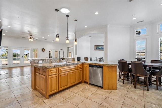 kitchen featuring pendant lighting, stainless steel dishwasher, sink, and an island with sink