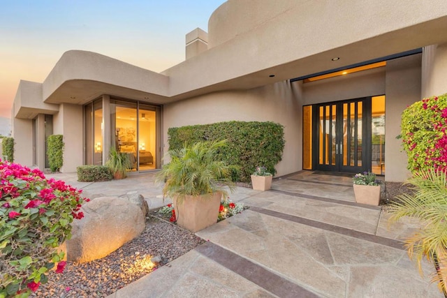 exterior entry at dusk with french doors and a patio area