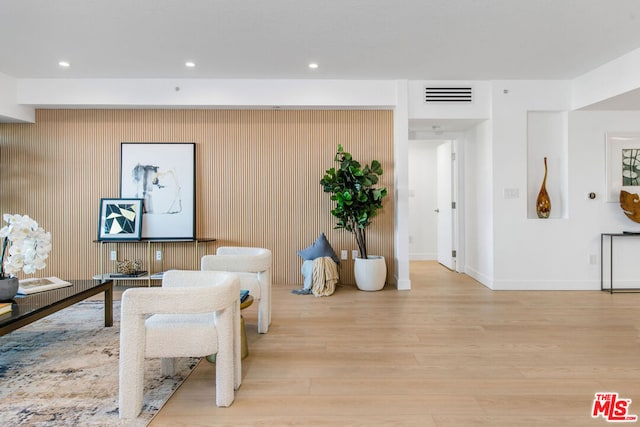 living room with wooden walls and light hardwood / wood-style floors