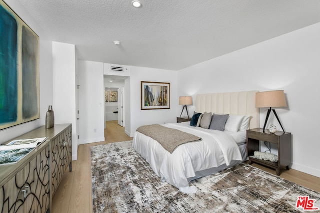 bedroom featuring a textured ceiling and light hardwood / wood-style flooring