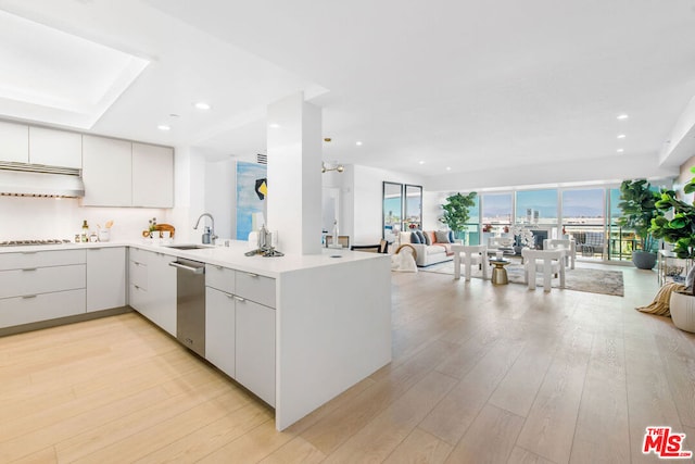 kitchen with sink, white cabinetry, light hardwood / wood-style floors, stainless steel dishwasher, and kitchen peninsula