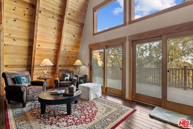 living area with beam ceiling, hardwood / wood-style flooring, and high vaulted ceiling