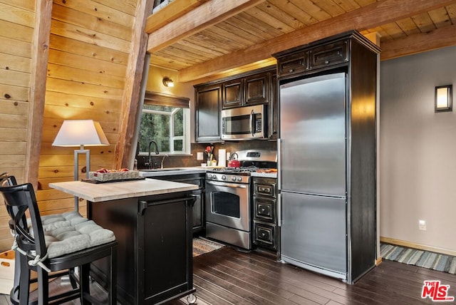 kitchen featuring a kitchen island, appliances with stainless steel finishes, beamed ceiling, sink, and dark wood-type flooring