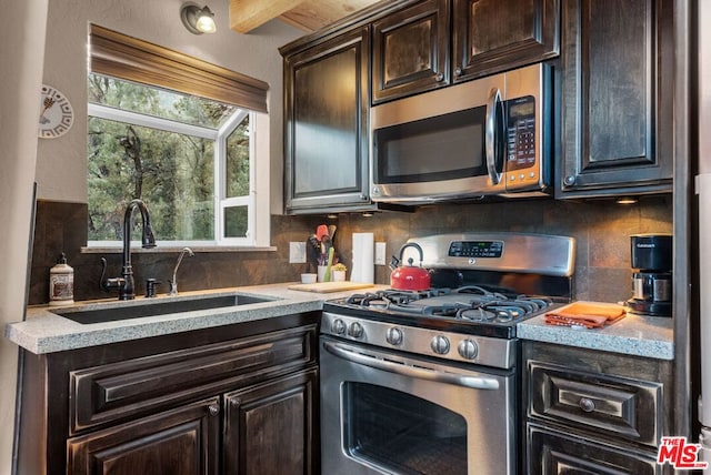 kitchen with tasteful backsplash, sink, dark brown cabinets, and appliances with stainless steel finishes