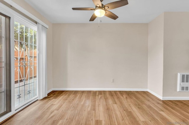 unfurnished room featuring heating unit, ceiling fan, and light wood-type flooring