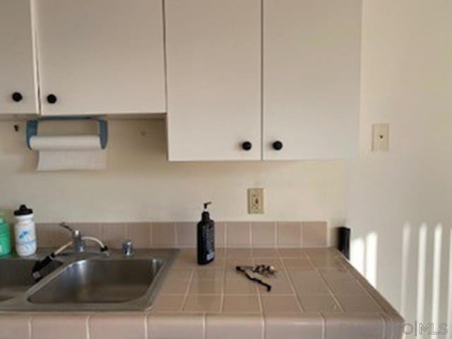 interior space featuring white cabinetry, sink, and tile counters