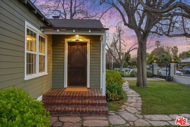 exterior entry at dusk featuring a lawn