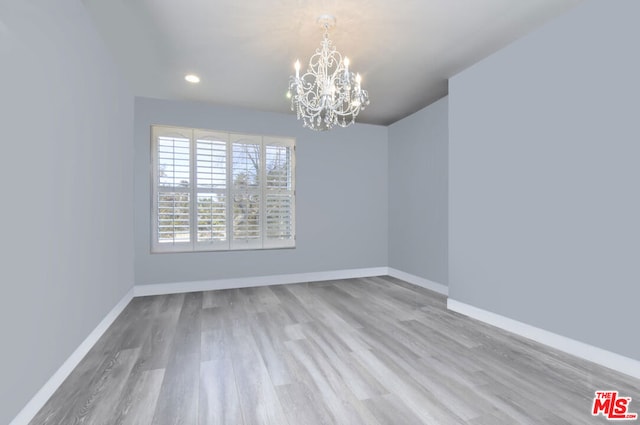 unfurnished room featuring an inviting chandelier and wood-type flooring