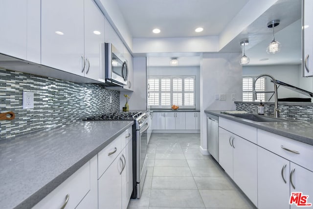 kitchen with decorative light fixtures, sink, white cabinets, decorative backsplash, and stainless steel appliances