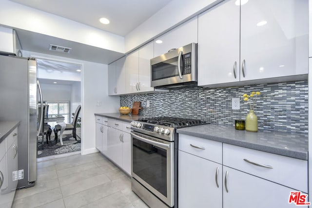 kitchen with stainless steel appliances, white cabinetry, tasteful backsplash, and light tile patterned floors