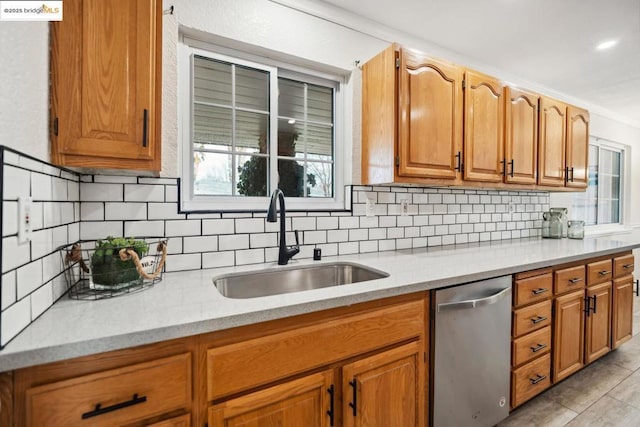 kitchen featuring light stone counters, sink, decorative backsplash, and stainless steel dishwasher