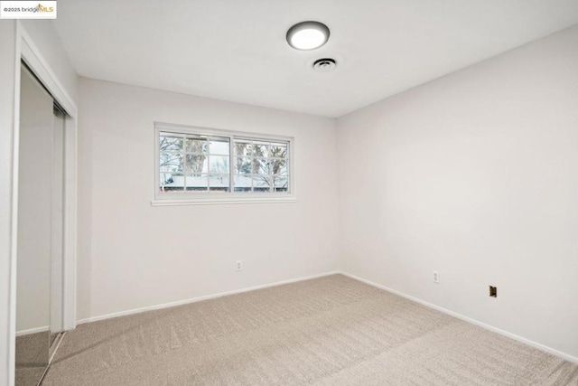 unfurnished bedroom featuring light carpet and a closet