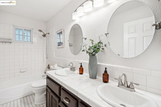 full bathroom with tiled shower / bath combo, vanity, and toilet