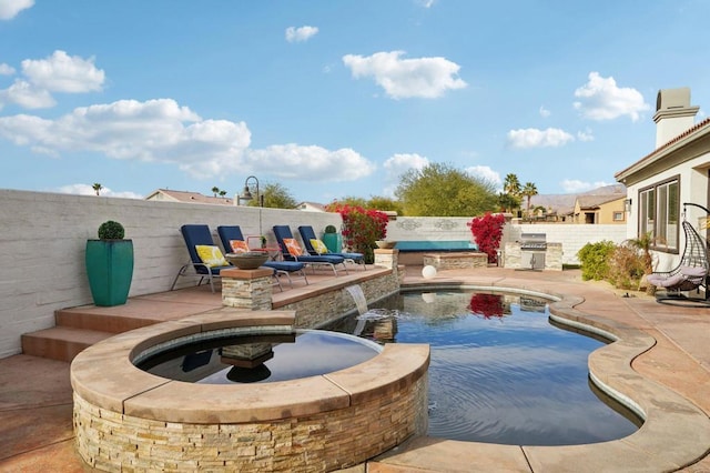 view of swimming pool with an outdoor fire pit, a patio area, pool water feature, and exterior kitchen