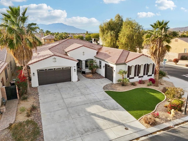 mediterranean / spanish-style house featuring a mountain view, a garage, and a front lawn