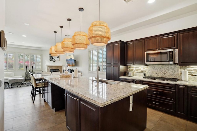 kitchen featuring pendant lighting, sink, decorative backsplash, a kitchen island with sink, and stainless steel appliances