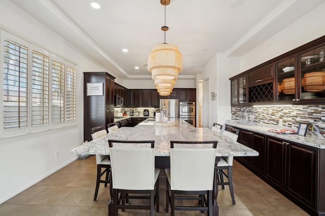 kitchen with appliances with stainless steel finishes, a kitchen island, a breakfast bar area, and hanging light fixtures