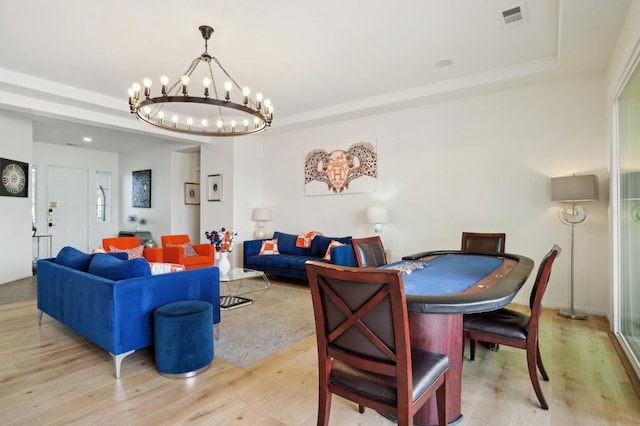 dining space with a tray ceiling and light hardwood / wood-style flooring