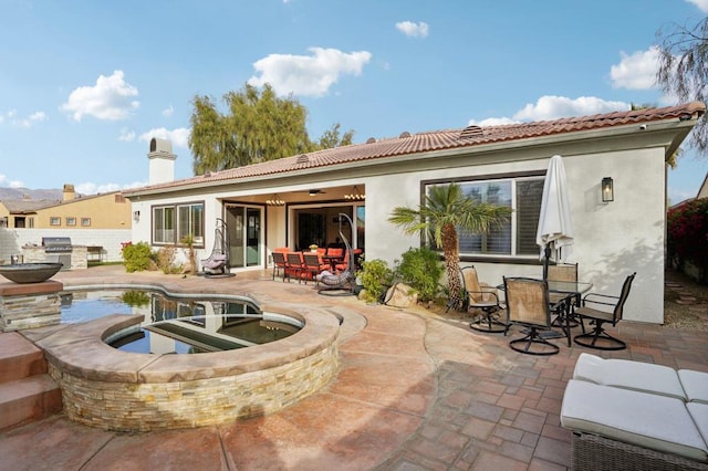 rear view of house with ceiling fan, exterior kitchen, a pool with hot tub, and a patio area