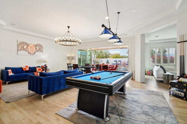 recreation room with an inviting chandelier, pool table, a raised ceiling, and light hardwood / wood-style flooring