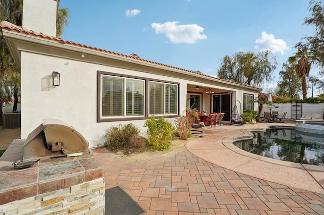 back of property featuring an outdoor kitchen, a fenced in pool, and a patio