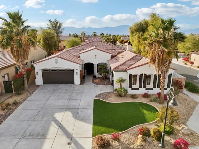 mediterranean / spanish-style home with a mountain view, a garage, and a front yard