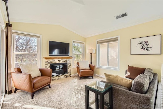 living room featuring vaulted ceiling, a tile fireplace, a healthy amount of sunlight, and carpet