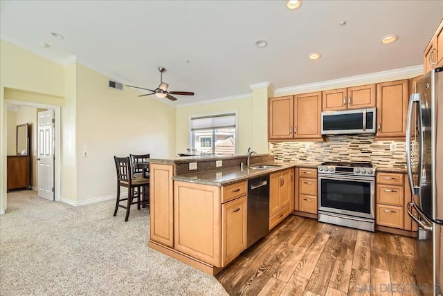 kitchen with sink, stone countertops, appliances with stainless steel finishes, kitchen peninsula, and decorative backsplash