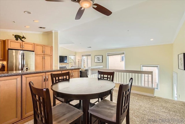 carpeted dining room featuring crown molding and lofted ceiling