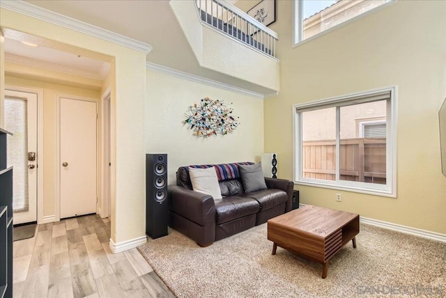 living room featuring plenty of natural light, ornamental molding, and light wood-type flooring