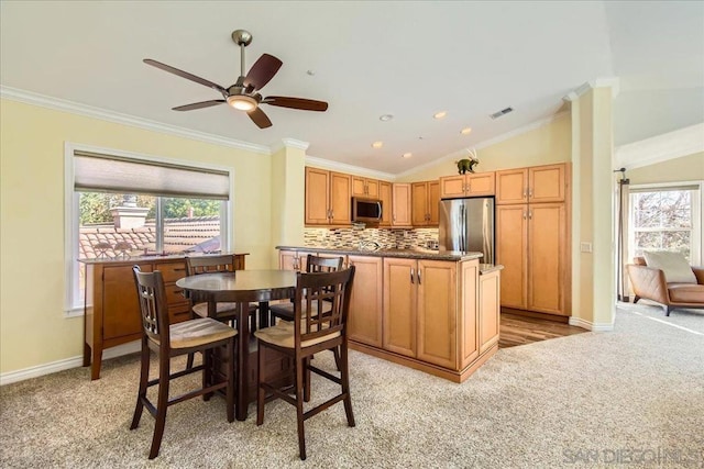 carpeted dining room featuring vaulted ceiling, ornamental molding, and ceiling fan