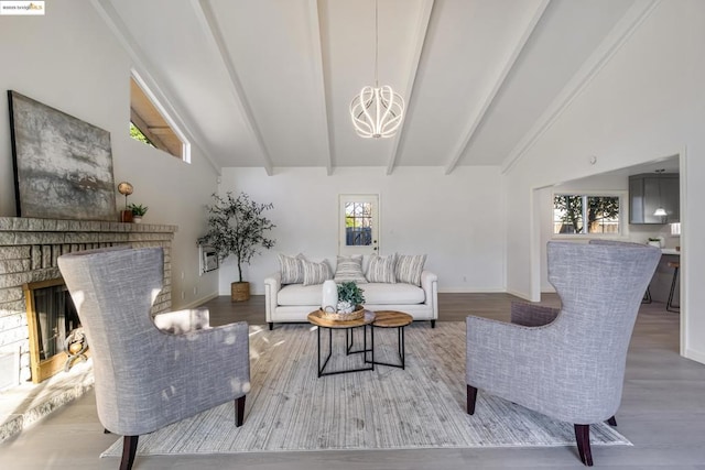 living room with hardwood / wood-style floors, lofted ceiling with beams, a brick fireplace, and a notable chandelier