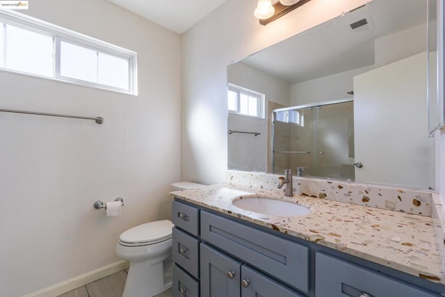 bathroom featuring vanity, toilet, and a shower with shower door