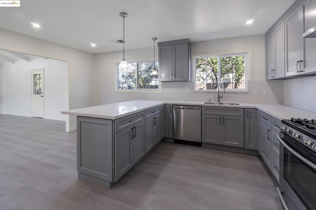 kitchen with appliances with stainless steel finishes, kitchen peninsula, sink, and gray cabinetry