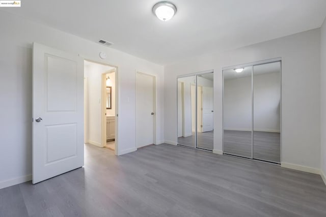 unfurnished bedroom with two closets and hardwood / wood-style flooring