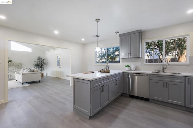 kitchen featuring sink, gray cabinets, dishwasher, kitchen peninsula, and pendant lighting